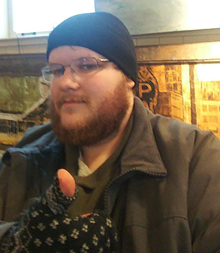 Photo of me, Robin VanGilder, wearing a winter hat and finerless mittens, giving a thumbs-up