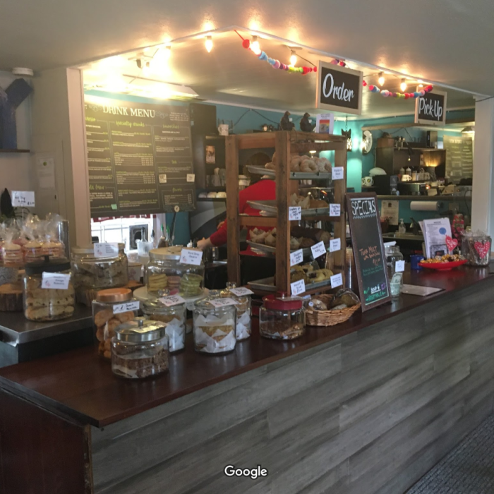 The counter at a coffee shop, with a glass case for pastries and an espresso machine.